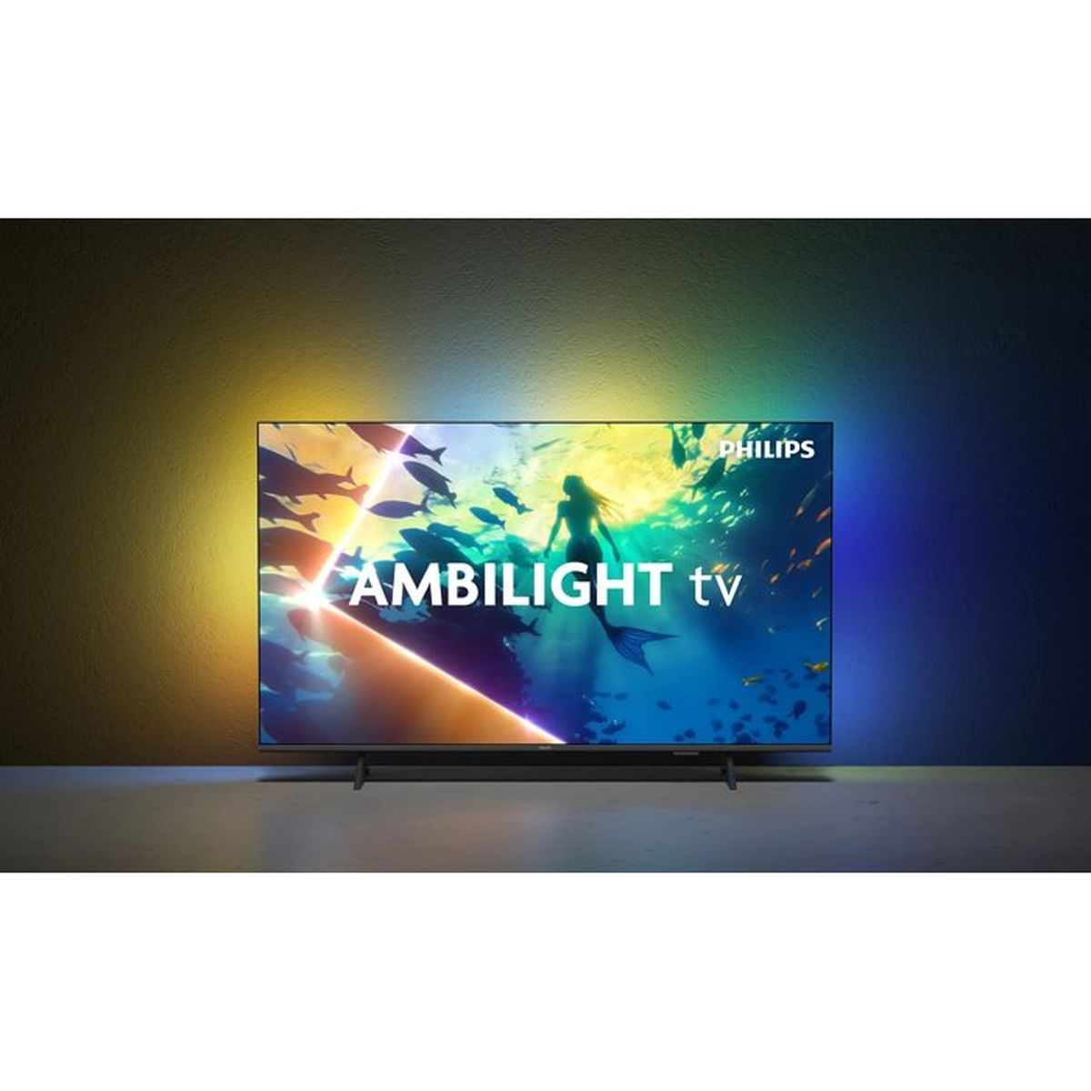 Un téléviseur Philips Ambilight sur une table projette une lumière colorée sur le mur.