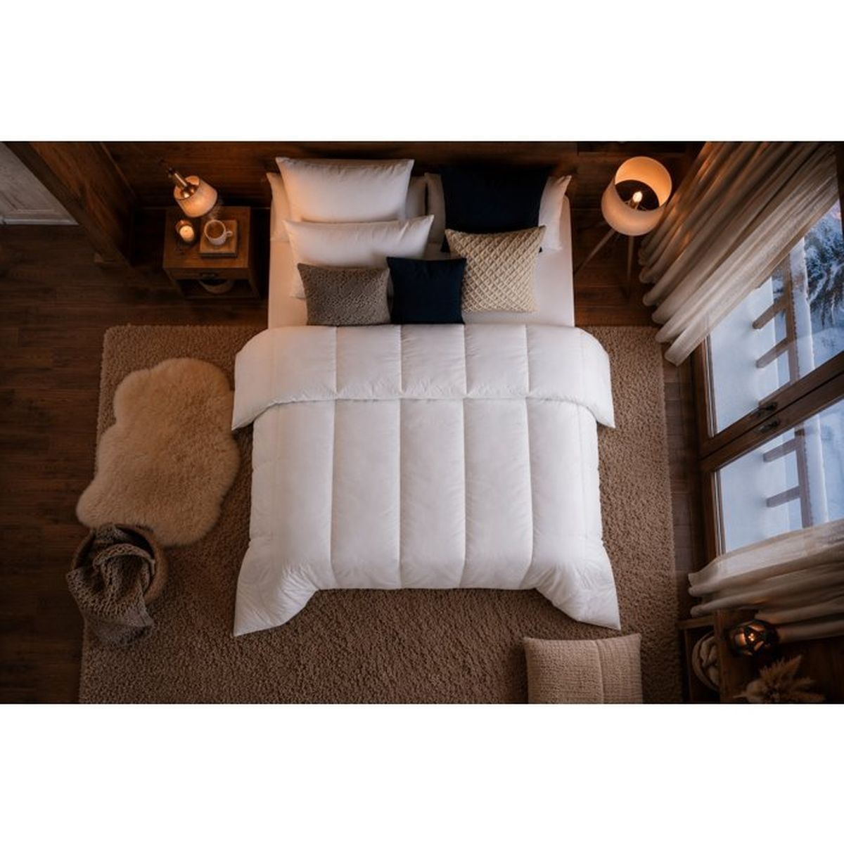 Gemütliches Schlafzimmer von oben mit weißem Bett, Kissen, Teppich und Holzwänden.