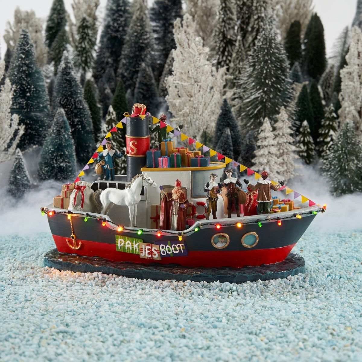 Pakjesboot model met Sinterklaas, een paard en cadeautjes te midden van besneeuwde dennenbomen.