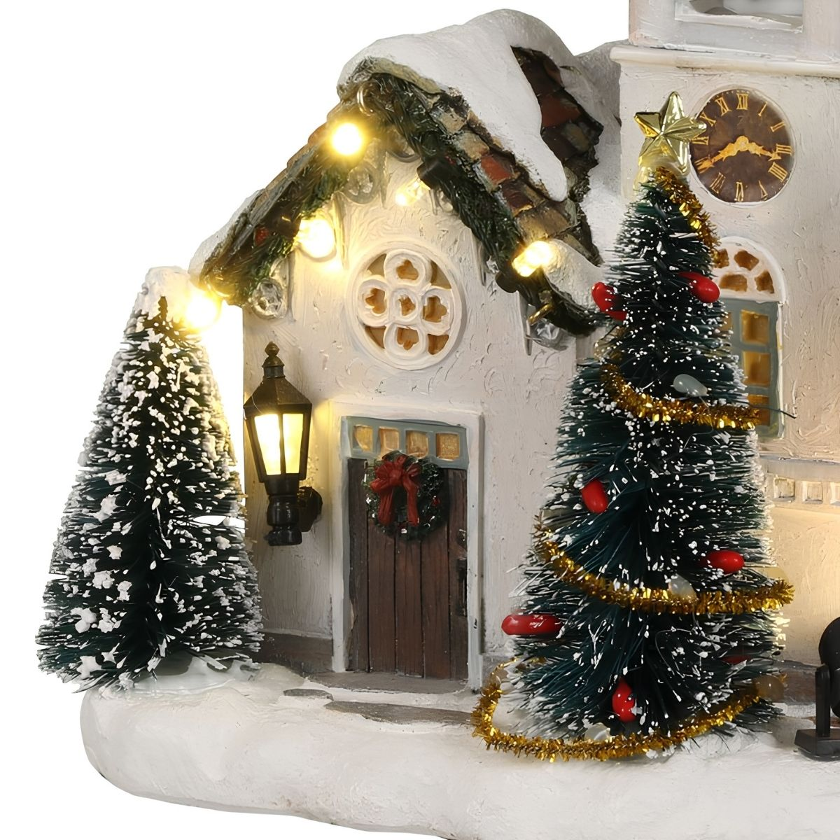 Een besneeuwd kerstdorp huis met verlichte bomen, een krans, warm licht en een klokkentoren.