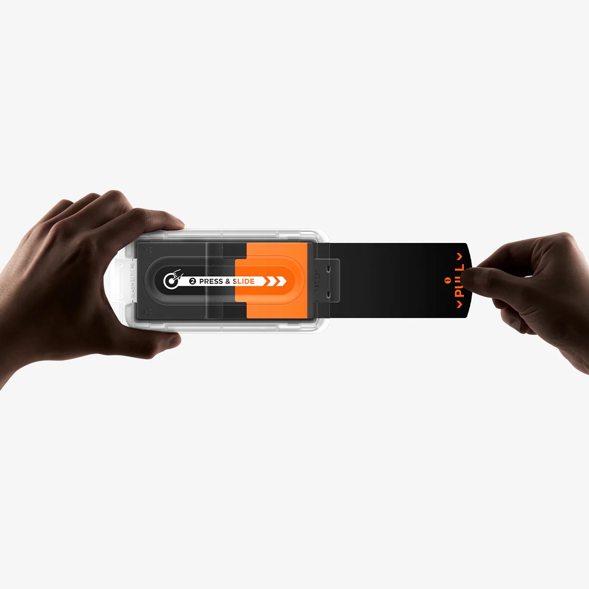 Hands hold a screen protector installation tray and pull out a black cover tab.
