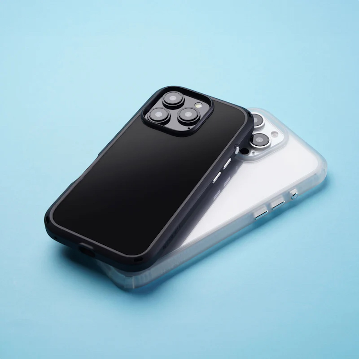 Zwei Smartphones in Schutzhüllen liegen auf einer blauen Oberfläche, das obere mit schwarzem Bumper.