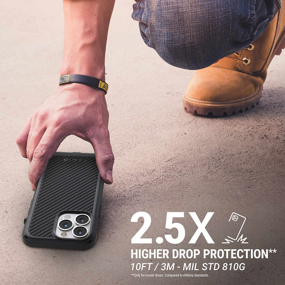 Hand greift nach einem Smartphone im Schutzgehäuse auf dem Boden neben einem Stiefel.