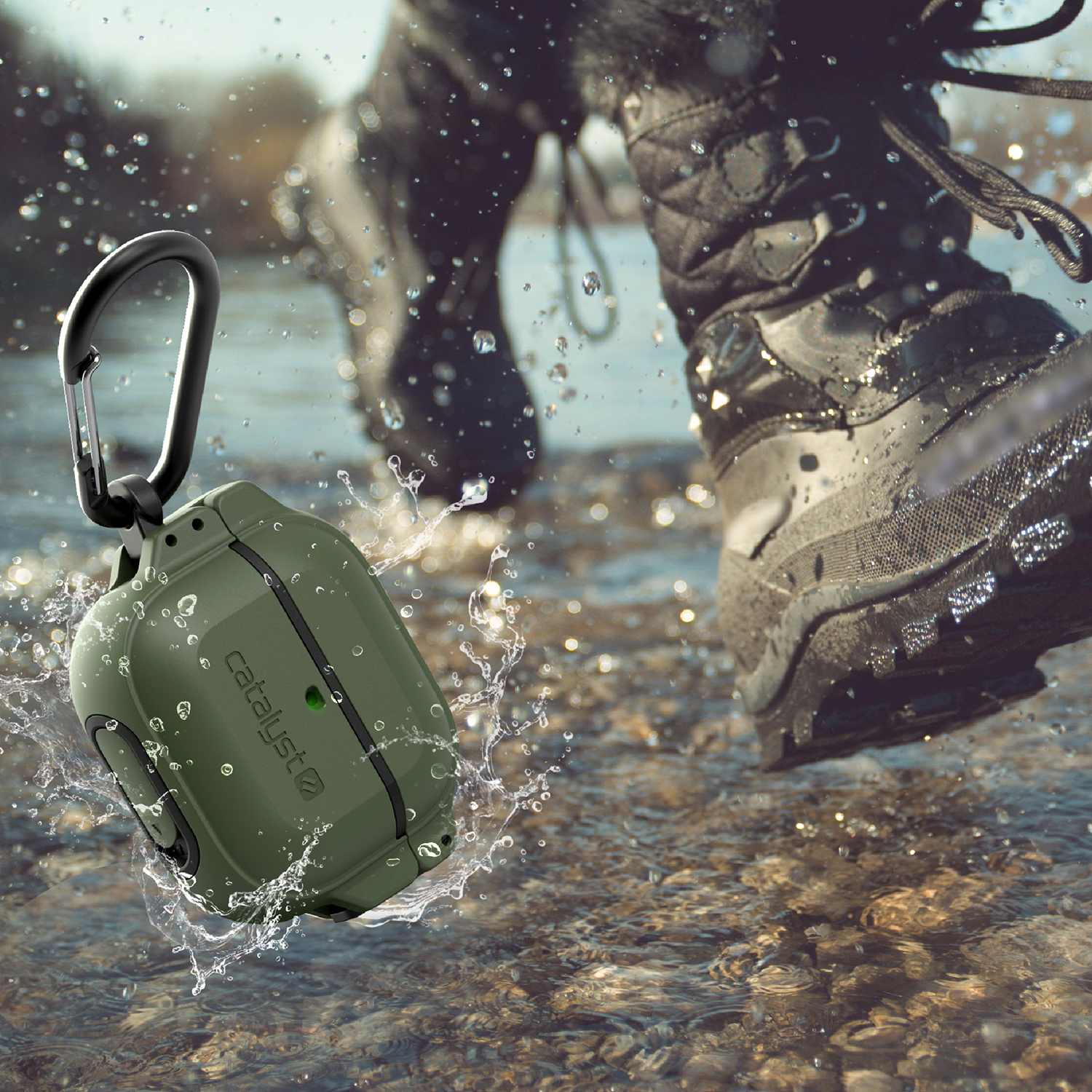 Eine olivgrüne Kopfhörerhülle mit Karabiner springt durch spritziges Wasser, während im Hintergrund Stiefel laufen.