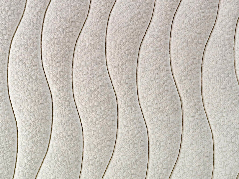 Patrón de ondas repetitivo en una superficie de colchón color crema con textura fina.