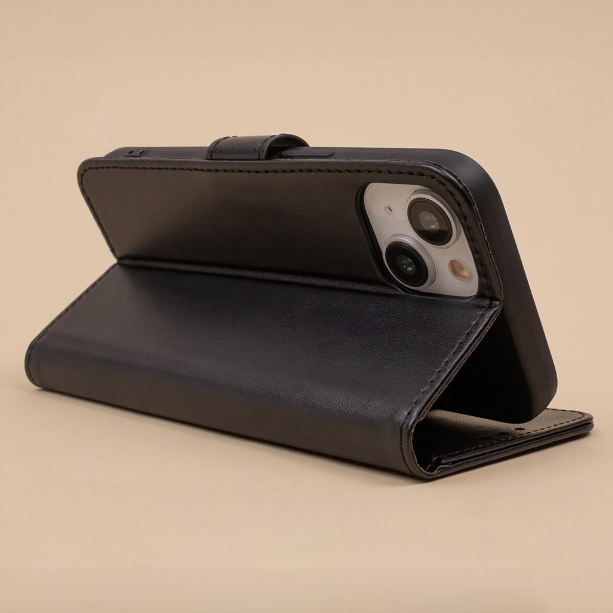 Ein schwarzes Leder-Flipcase für Smartphones steht offen und zeigt die Rückkamera auf einem beigen Hintergrund.