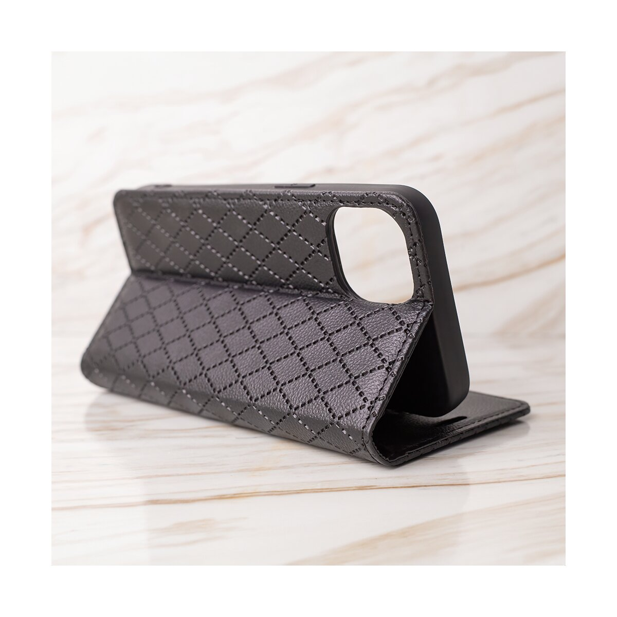 Eine schwarze Smartphone-Brieftasche aus Steppleder steht offen auf einer hellen Marmoroberfläche.