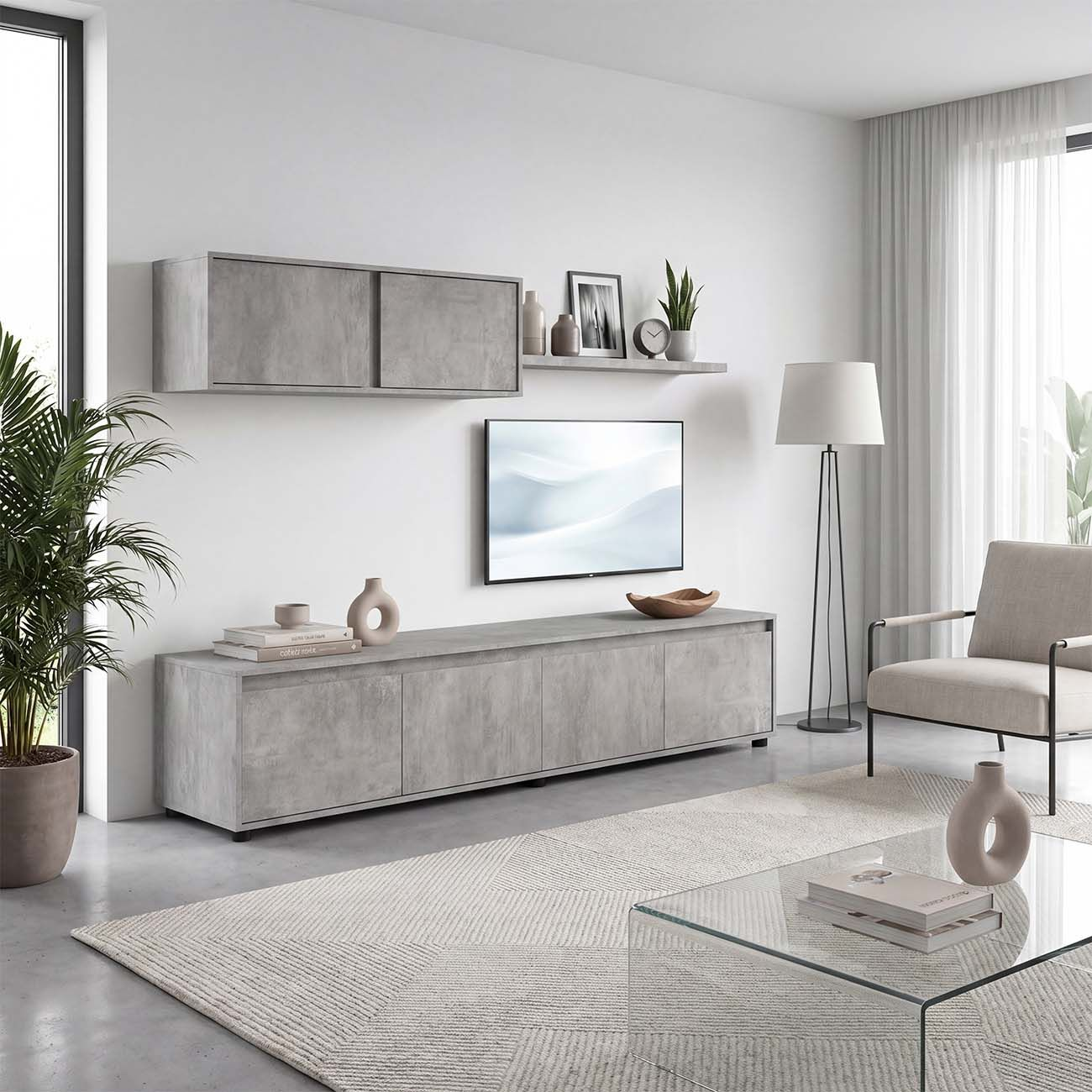 Mueble de TV gris moderno en pared blanca con televisor, estante, lámpara y sillón en una sala luminosa.
