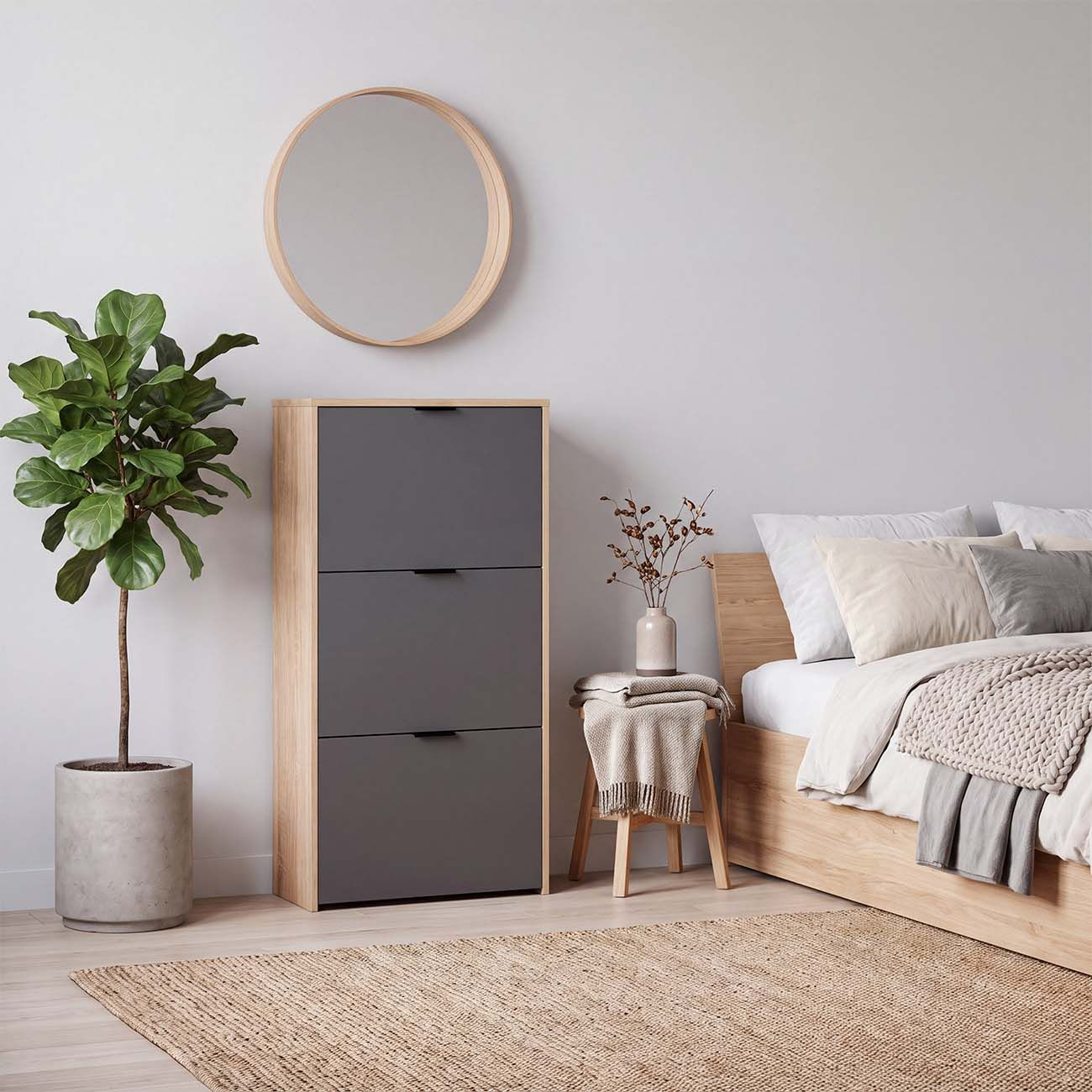 Un dormitorio moderno con armario gris, planta en maceta, espejo redondo, taburete de madera y cama con cojines.