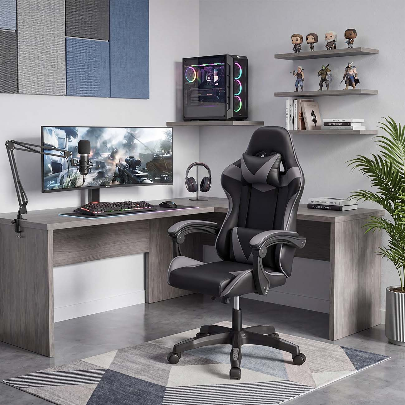 Un moderno equipo de juegos con escritorio en L, silla negra y gris, monitor grande y estantes con figuras.