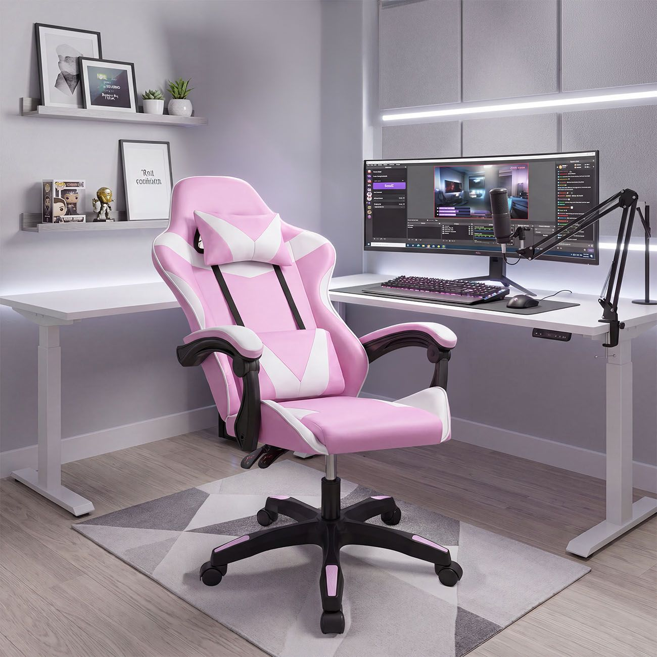Una silla de juego rosa y blanca frente a un escritorio blanco con monitor y micrófono.