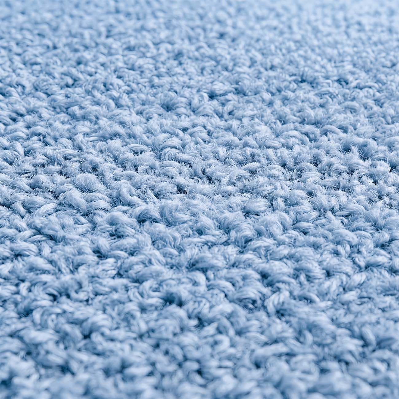 Vista cercana de la superficie de una alfombra esponjosa y azul claro.
