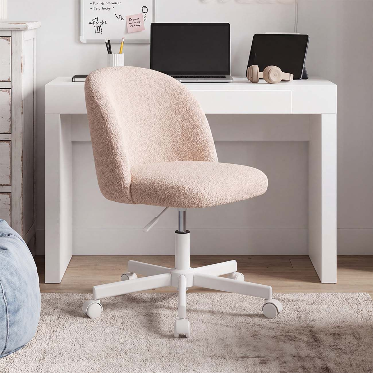 Una silla de oficina rosa claro y esponjosa con ruedas frente a un escritorio blanco.