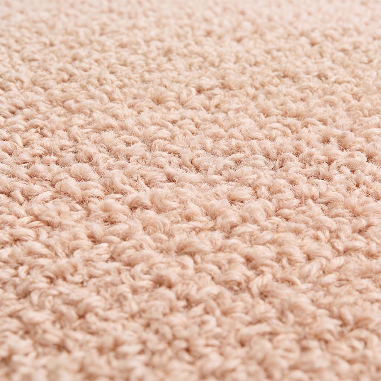 Primer plano de una textura de alfombra beige esponjosa con bucles suaves.
