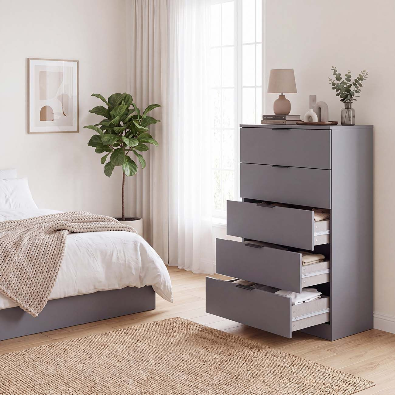 Un dormitorio moderno con una cómoda gris con los cajones inferiores abiertos y una cama a la izquierda.