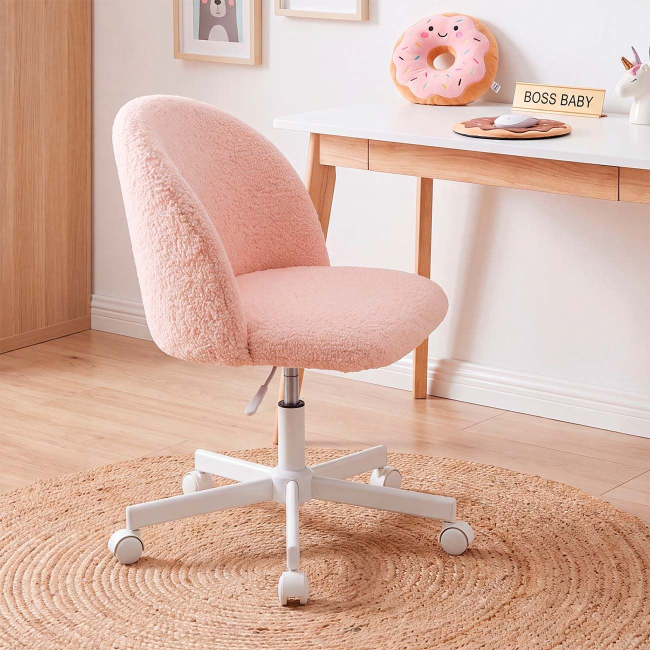 Una silla giratoria rosa esponjosa con patas blancas sobre una alfombra de yute frente a un escritorio blanco.