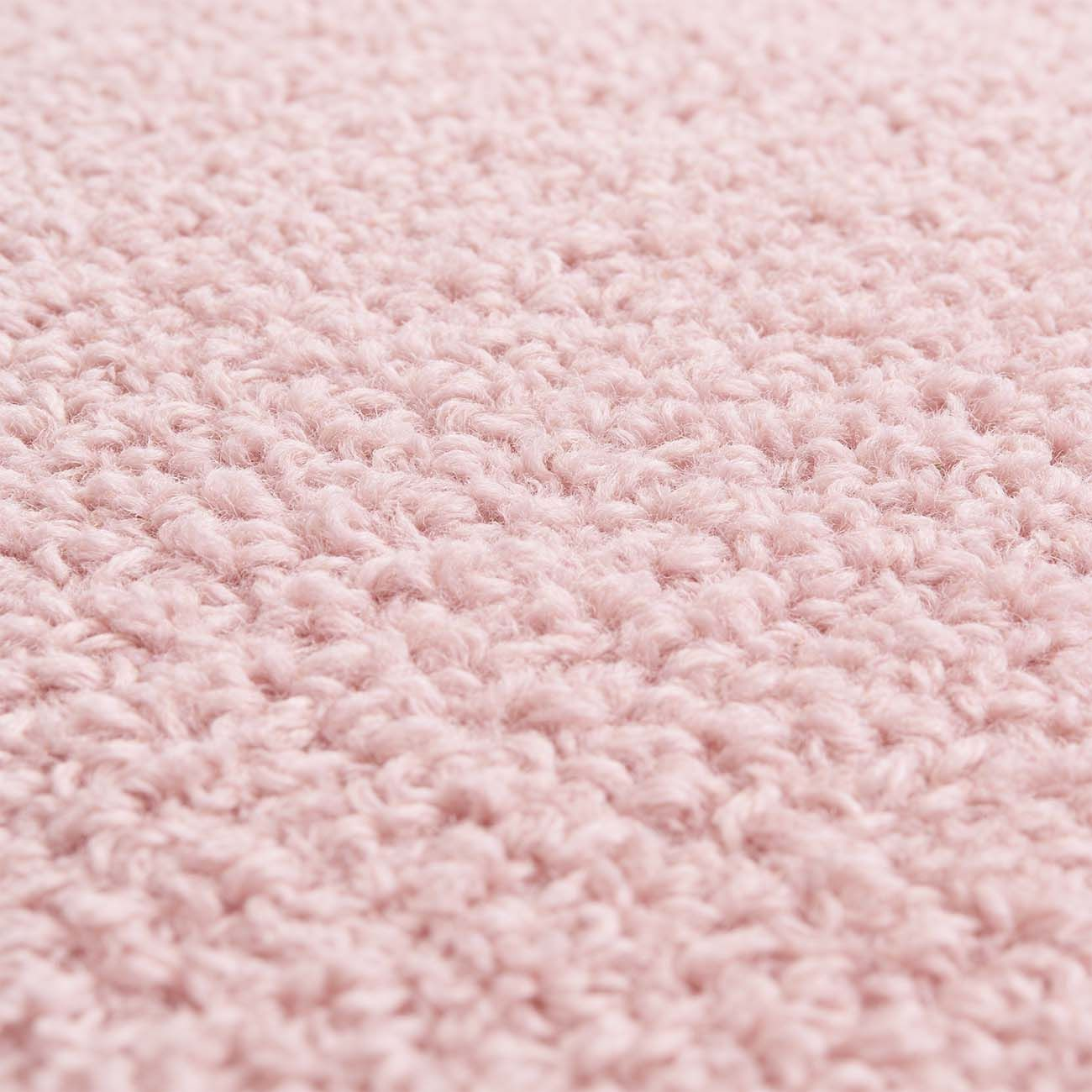 Vista de cerca de una textura de tela tejida de color rosa pálido y suave.