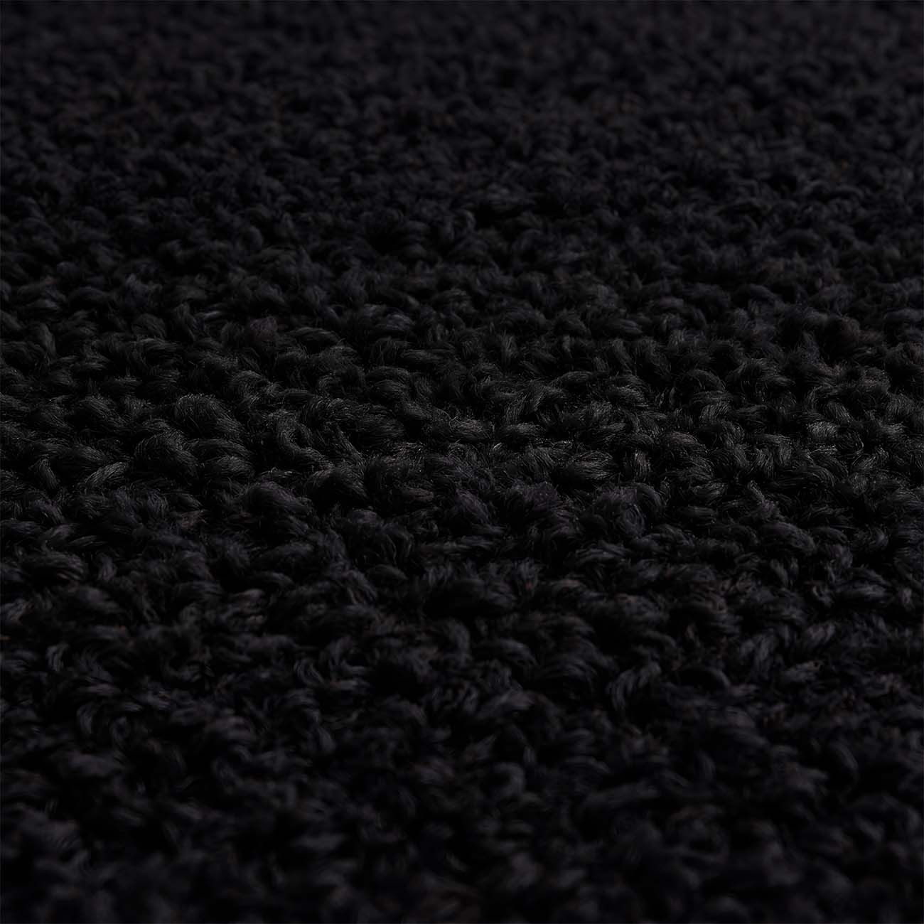 Primer plano de una superficie de alfombra oscura y texturizada.
