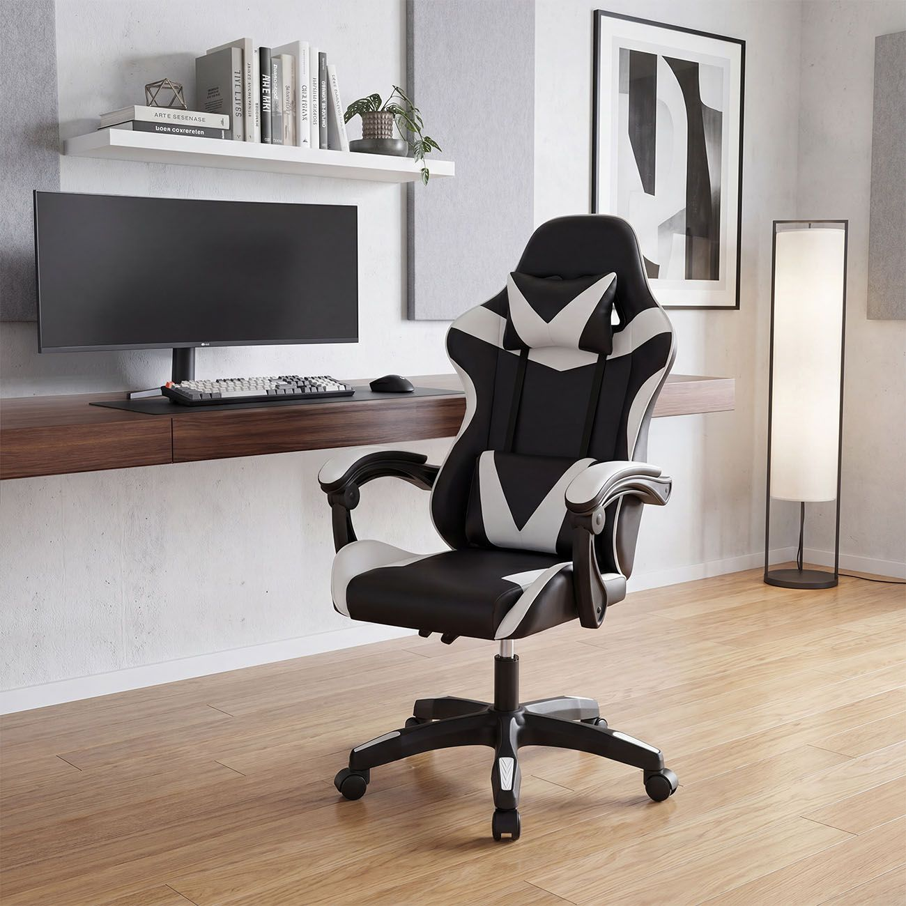 Una silla de juego en blanco y negro se encuentra en una oficina moderna con suelo de madera, escritorio y monitor.