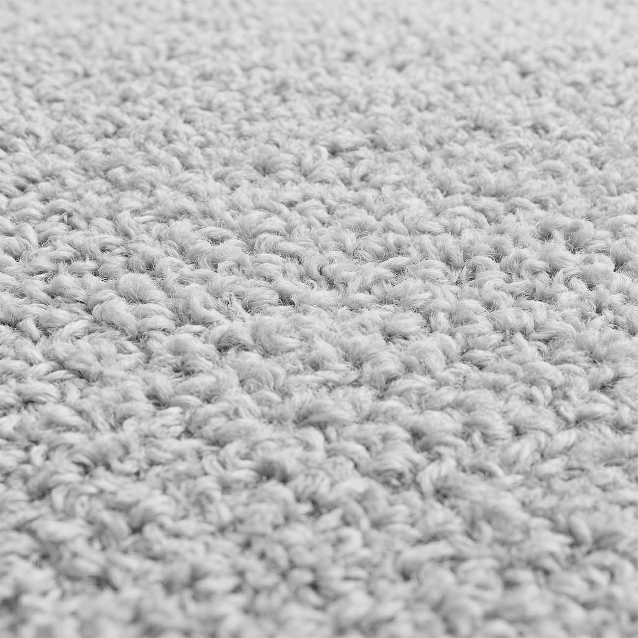 Primer plano de una tela tejida, gruesa y de color gris claro con fibras rizadas.