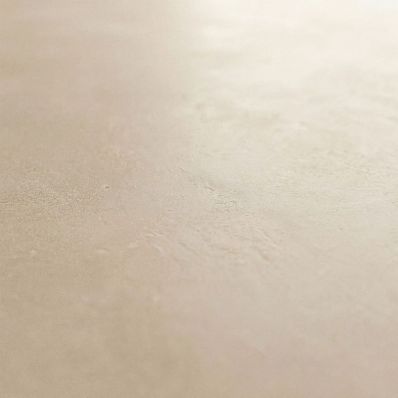 Primer plano de una superficie lisa de color beige con textura fina y luz suave.