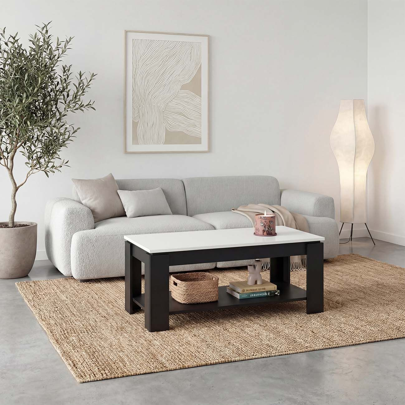 Una mesa de centro blanca y negra sobre una alfombra de yute en una sala luminosa con sofá gris.