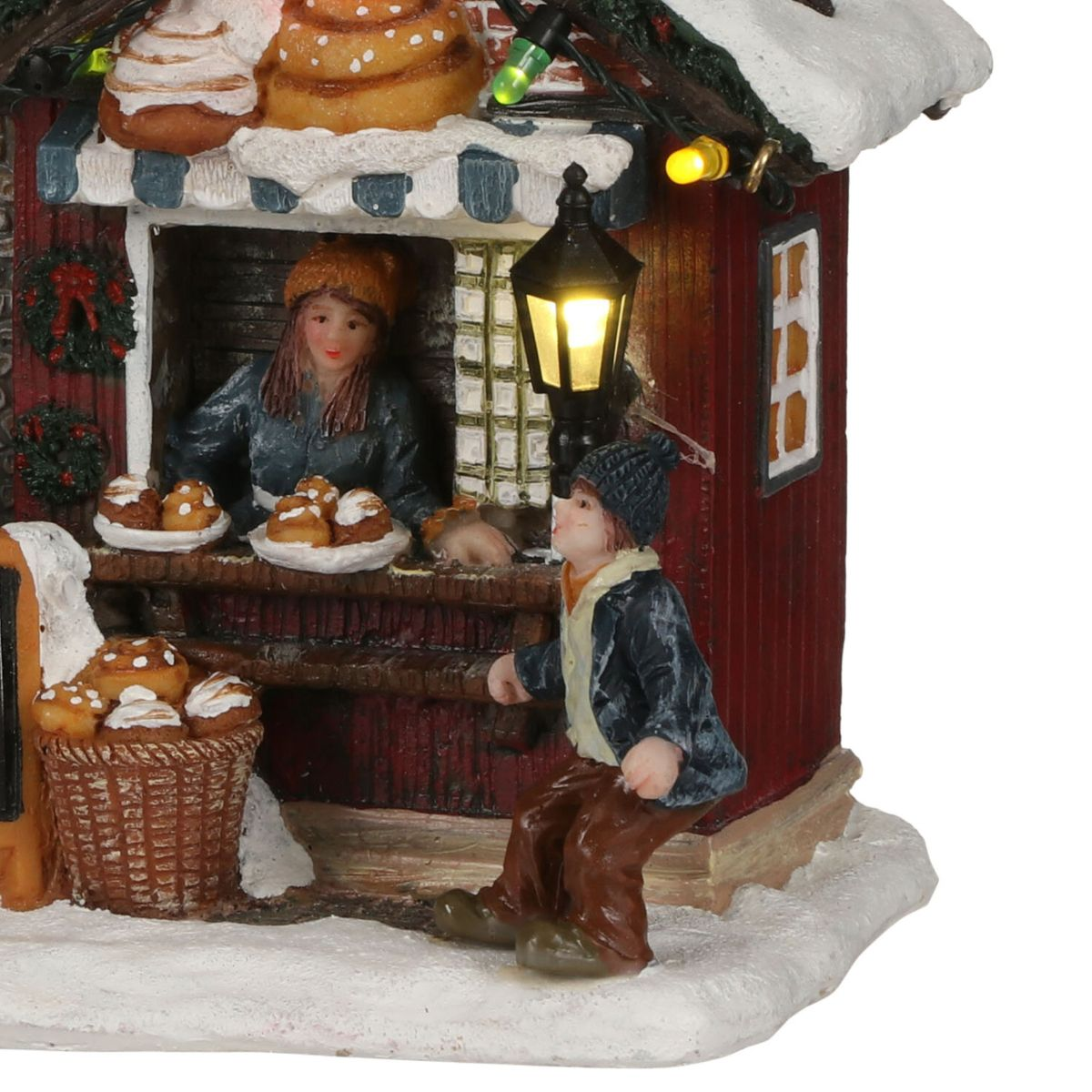 Een kersttafereel met een vrouwelijke bakker in een rode houten winkel en een jonge jongen buiten.