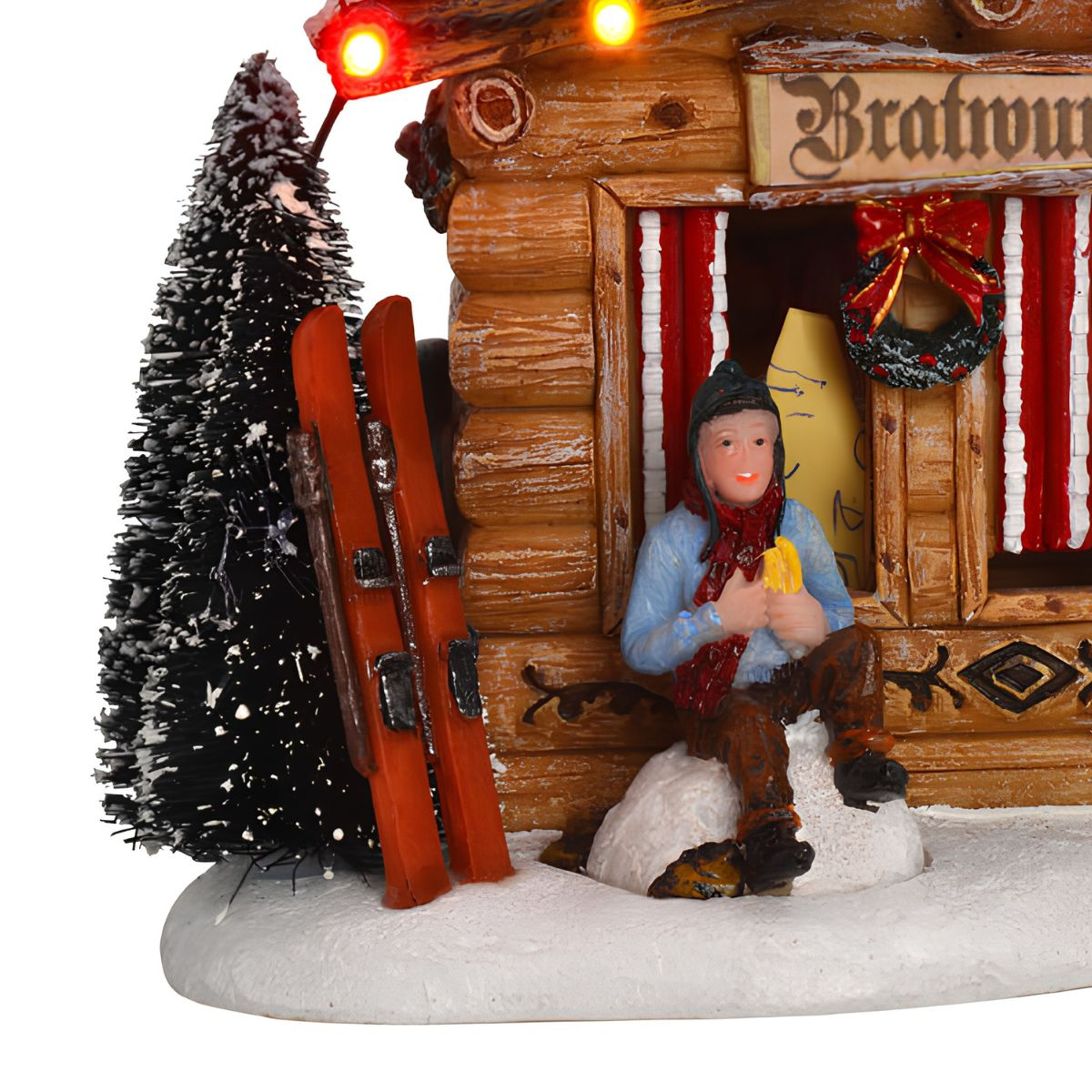 A ski chalet with a small figure, skis in the snow, and string lights.