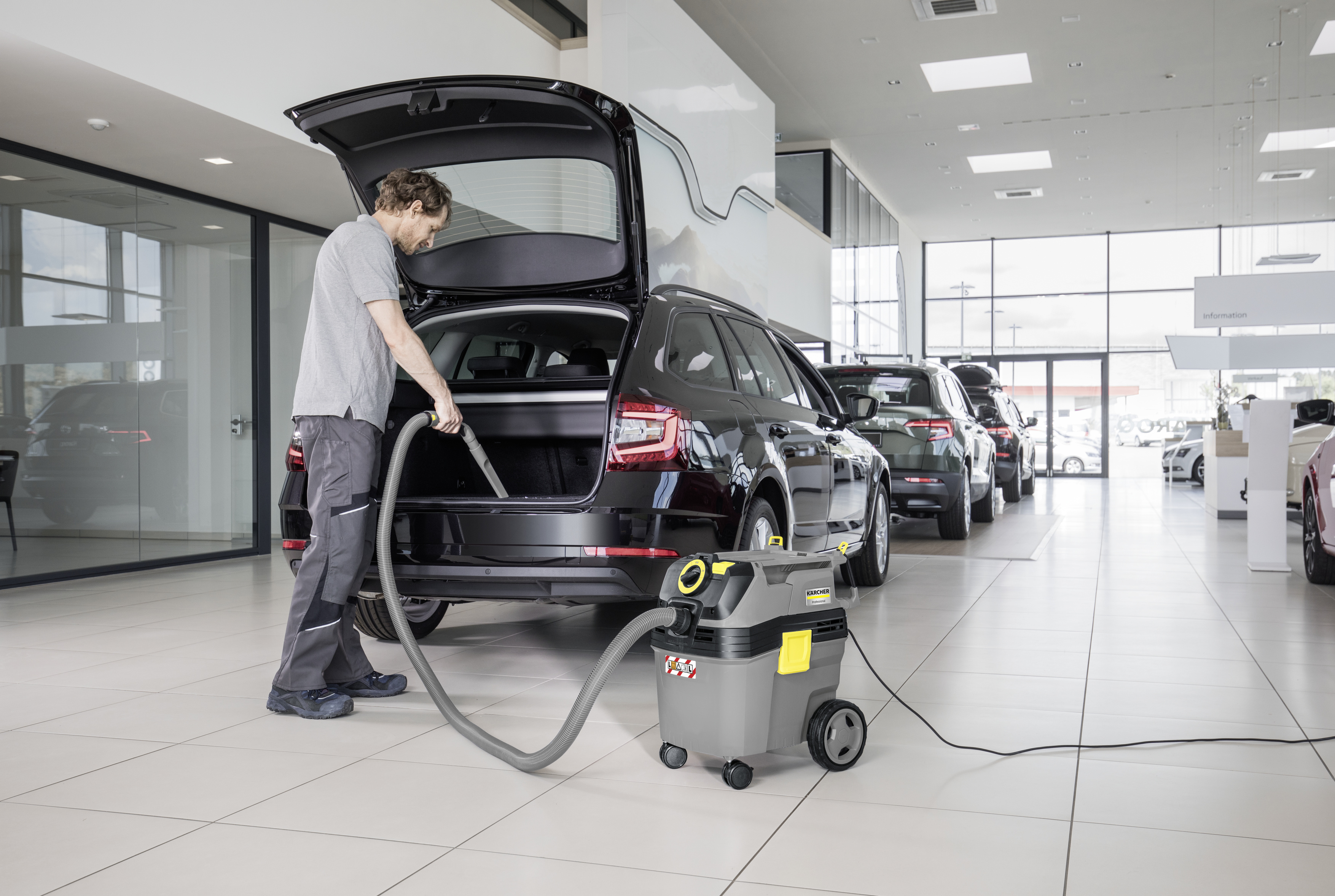 Un lavoratore aspira il bagagliaio di un'auto in una concessionaria.