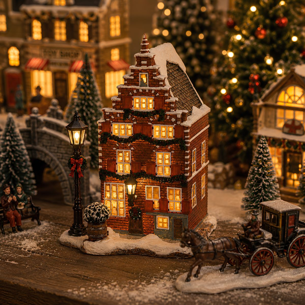 Miniatuur kerstdorp met verlicht bakstenen huis, koets, bomen en lantaarnpaal in de sneeuw.