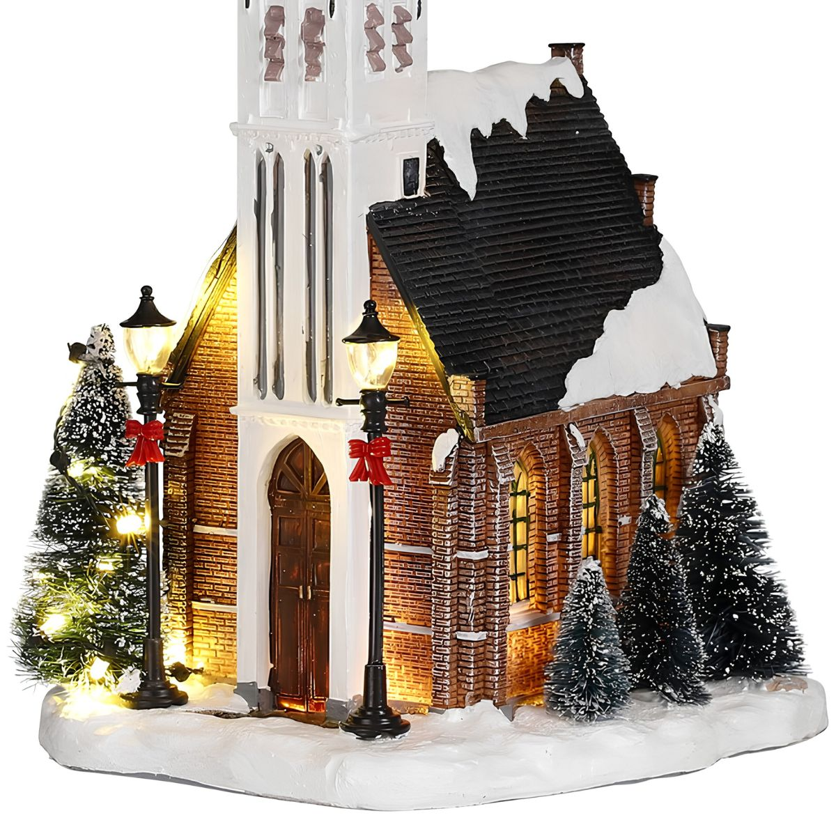 Model of a snow-covered church with lights and pine trees.