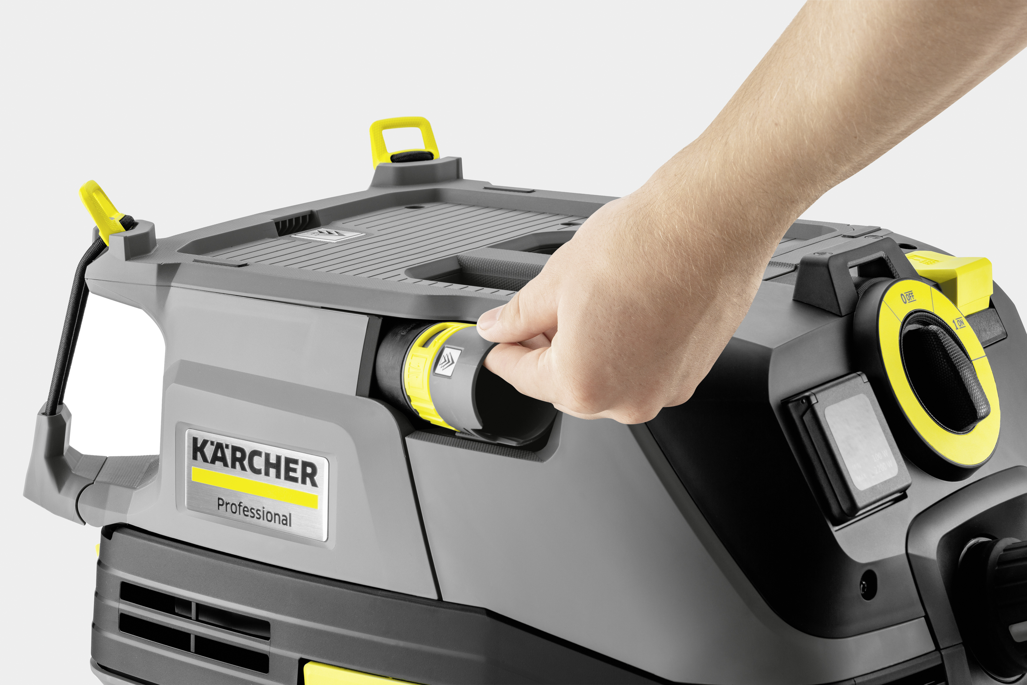 Una mano collega un tubo a un aspirapolvere Kärcher Professional grigio e giallo.
