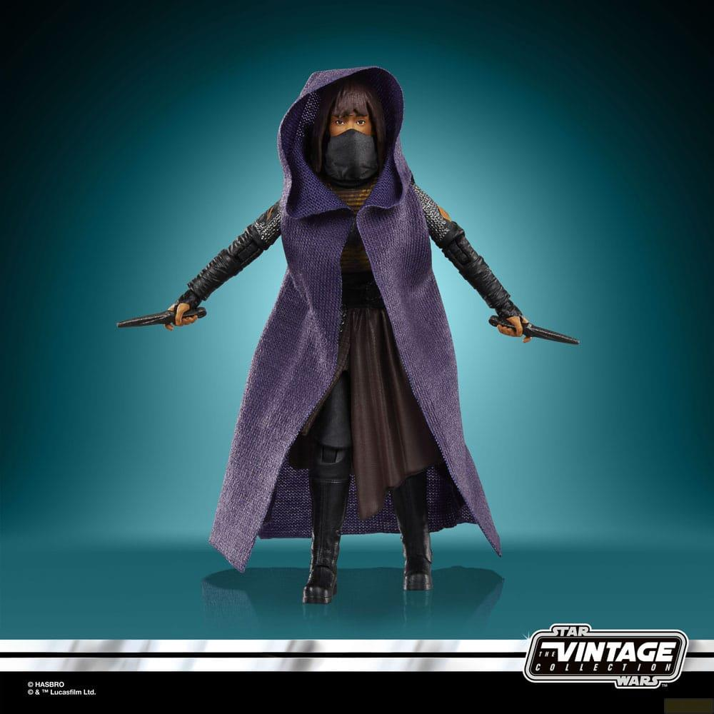 Eine Actionfigur in einem langen violetten Umhang mit Kapuze, schwarzer Maske und Messern in den Händen.