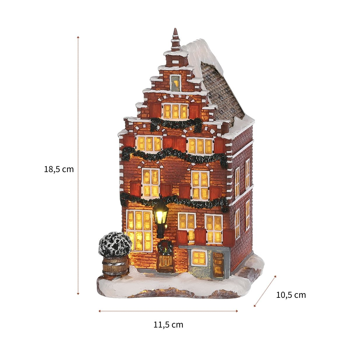 Verlicht kerstenstenen huis met sneeuw op het dak, versierd met slingers en maatpijlen.