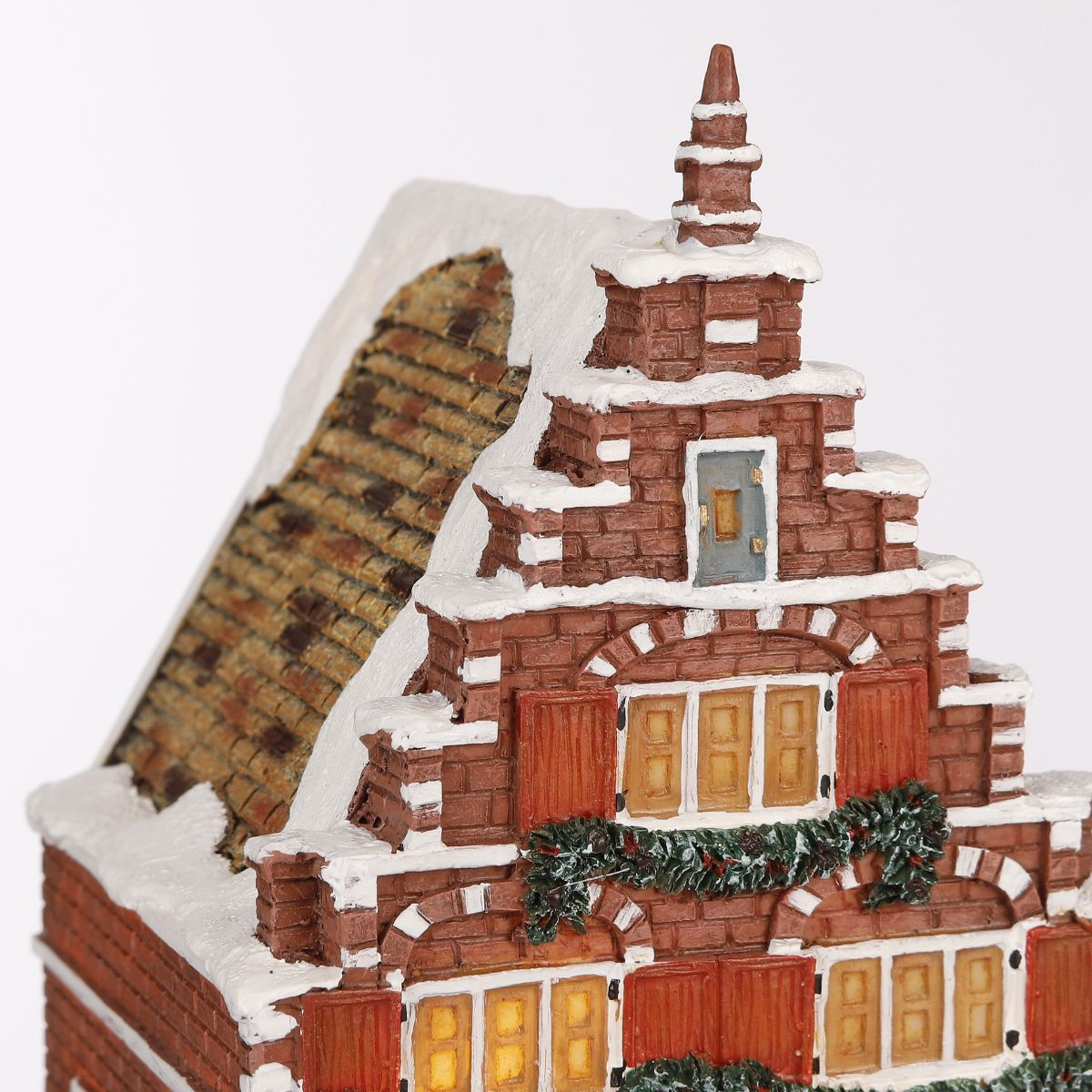 Miniatuur bakstenen huis met besneeuwde daken en decoratieve ramen.
