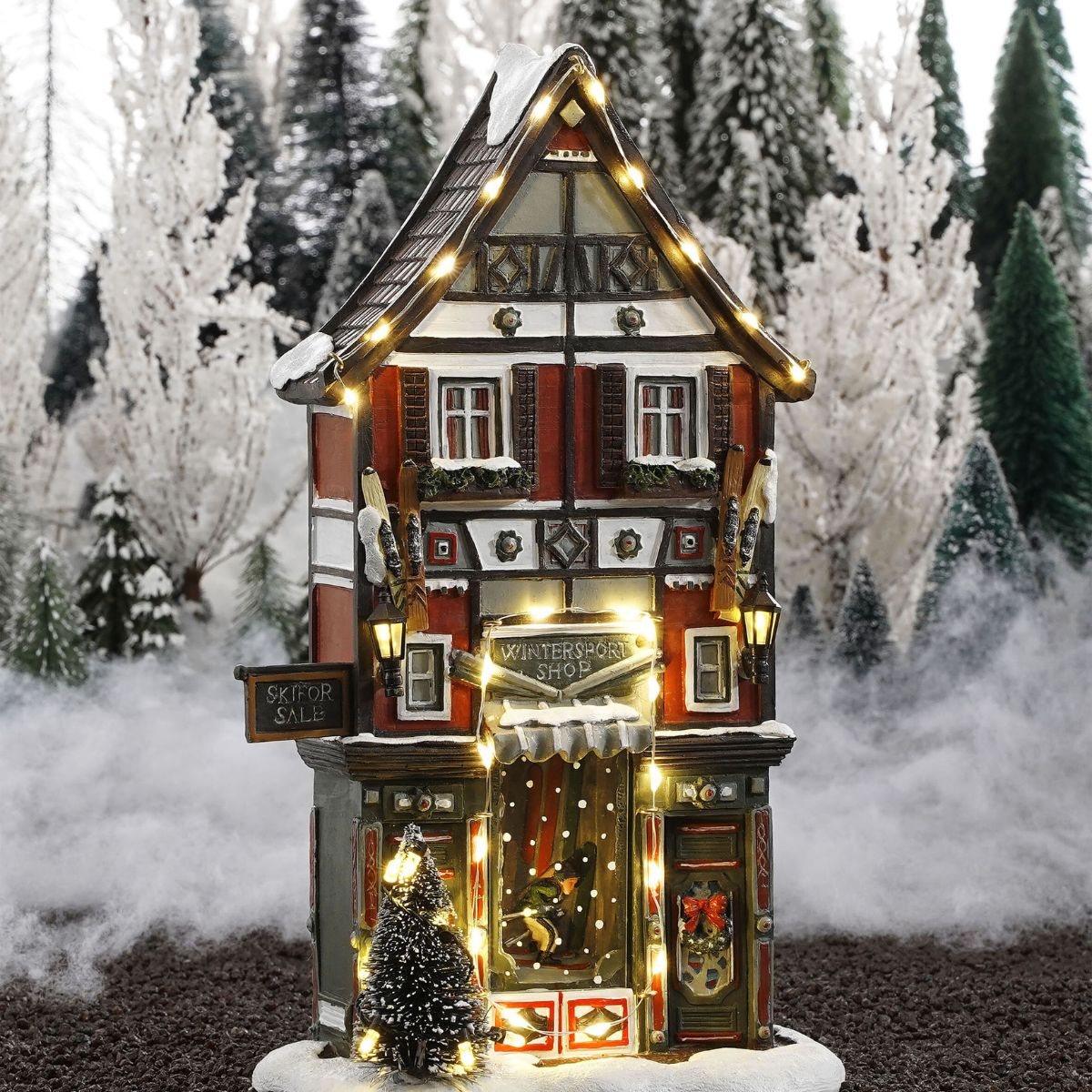 Modèle de maison de magasin de sports d'hiver illuminé dans la neige avec des arbres.