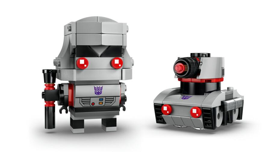 Silahlı gri bir robotun ve yanında küçük gri bir tankın Lego figürü.