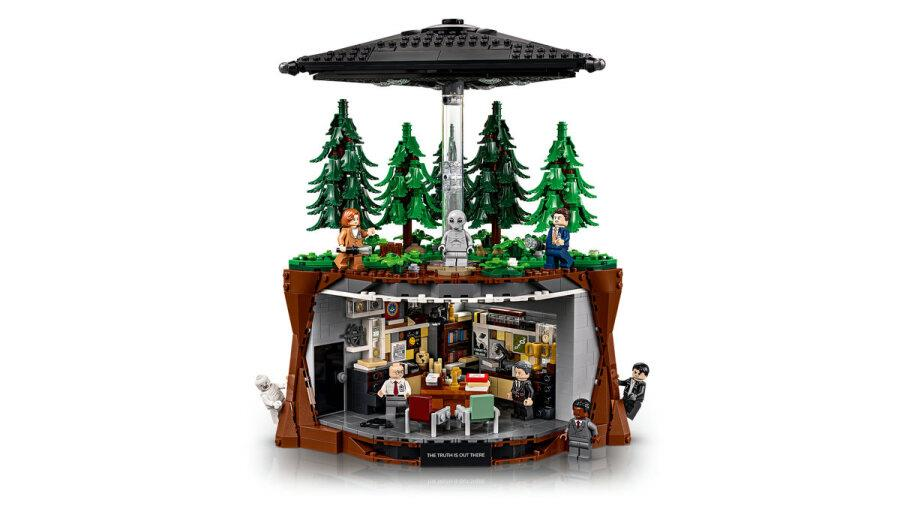 Modello Lego con una foresta in cima e una base segreta con minifigure in basso, sotto un UFO.