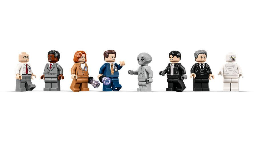 Una fila di otto minifigure LEGO tra cui agenti, un alieno e un mostro su sfondo bianco.