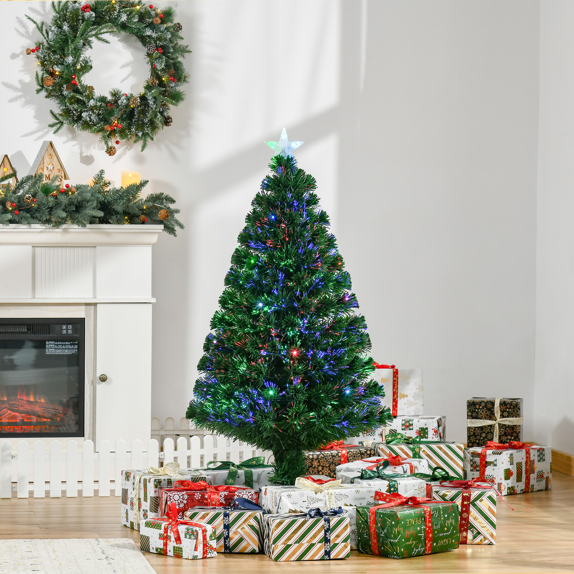 Un árbol de Navidad iluminado con luces de colores y una estrella, rodeado de regalos junto a una chimenea.