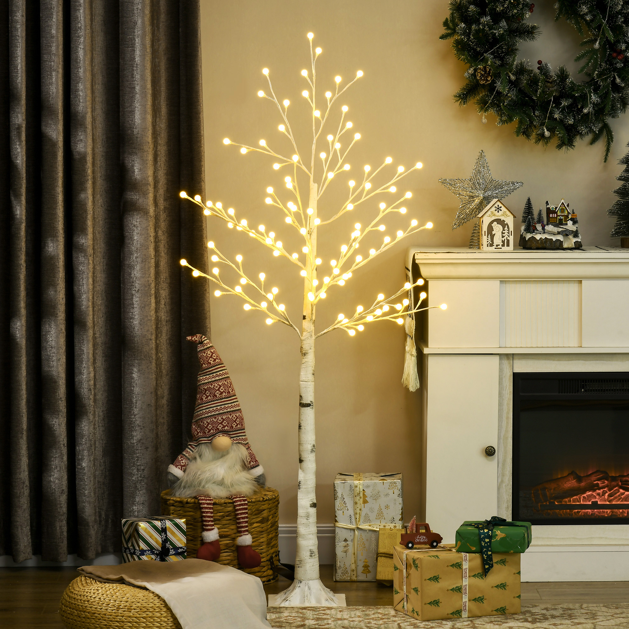 Árbol artificial iluminado con luces, regalos y decoración navideña en una sala.