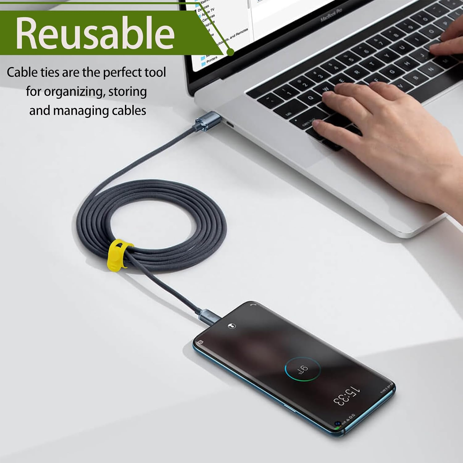 Ein Smartphone und ein aufgerolltes Kabel sind an einen Laptop angeschlossen. Ein gelber Kabelbinder sichert das Kabel.