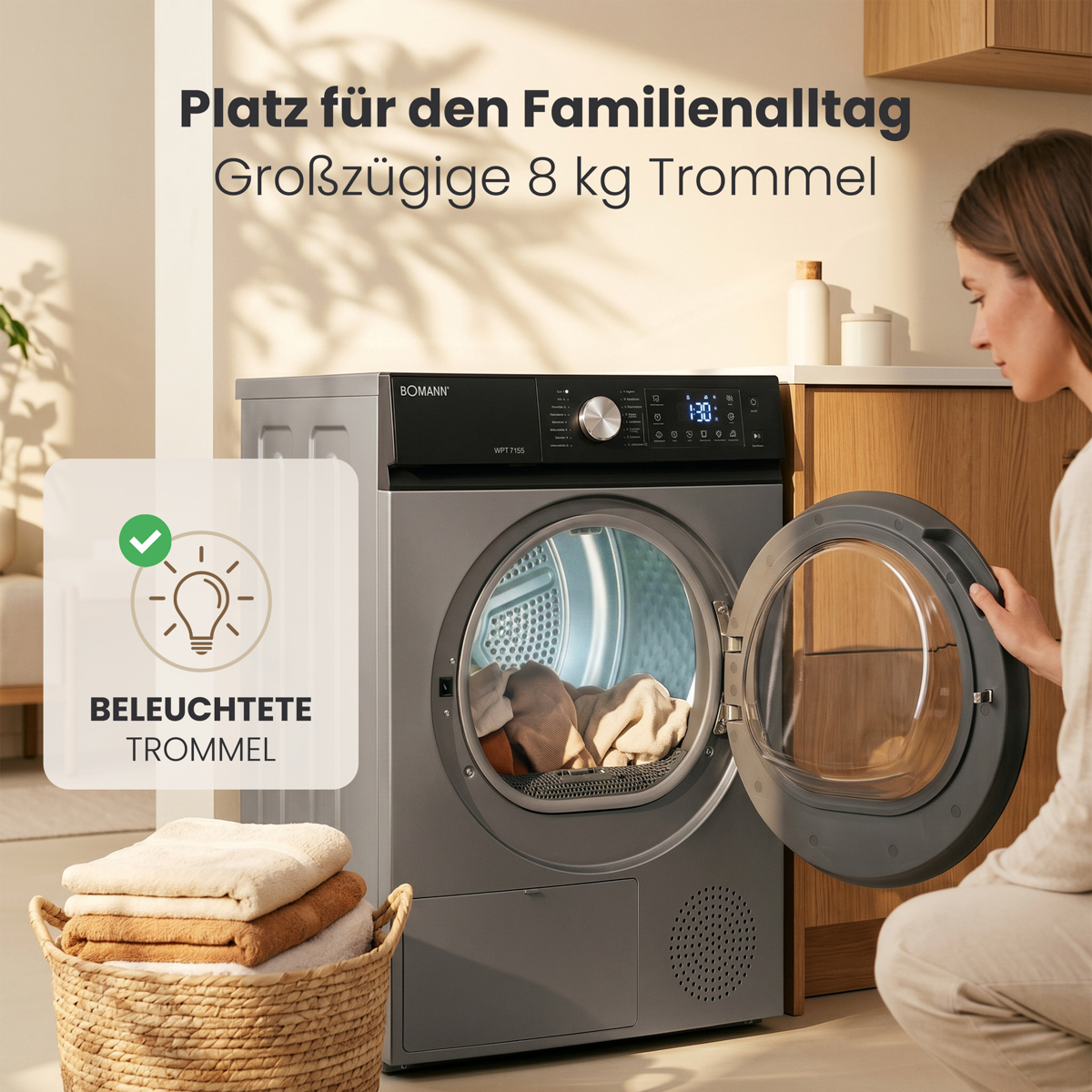Eine Frau öffnet die Trommel eines grauen Bomann Trockners mit erleuchtetem Innenraum und Wäschekorb.