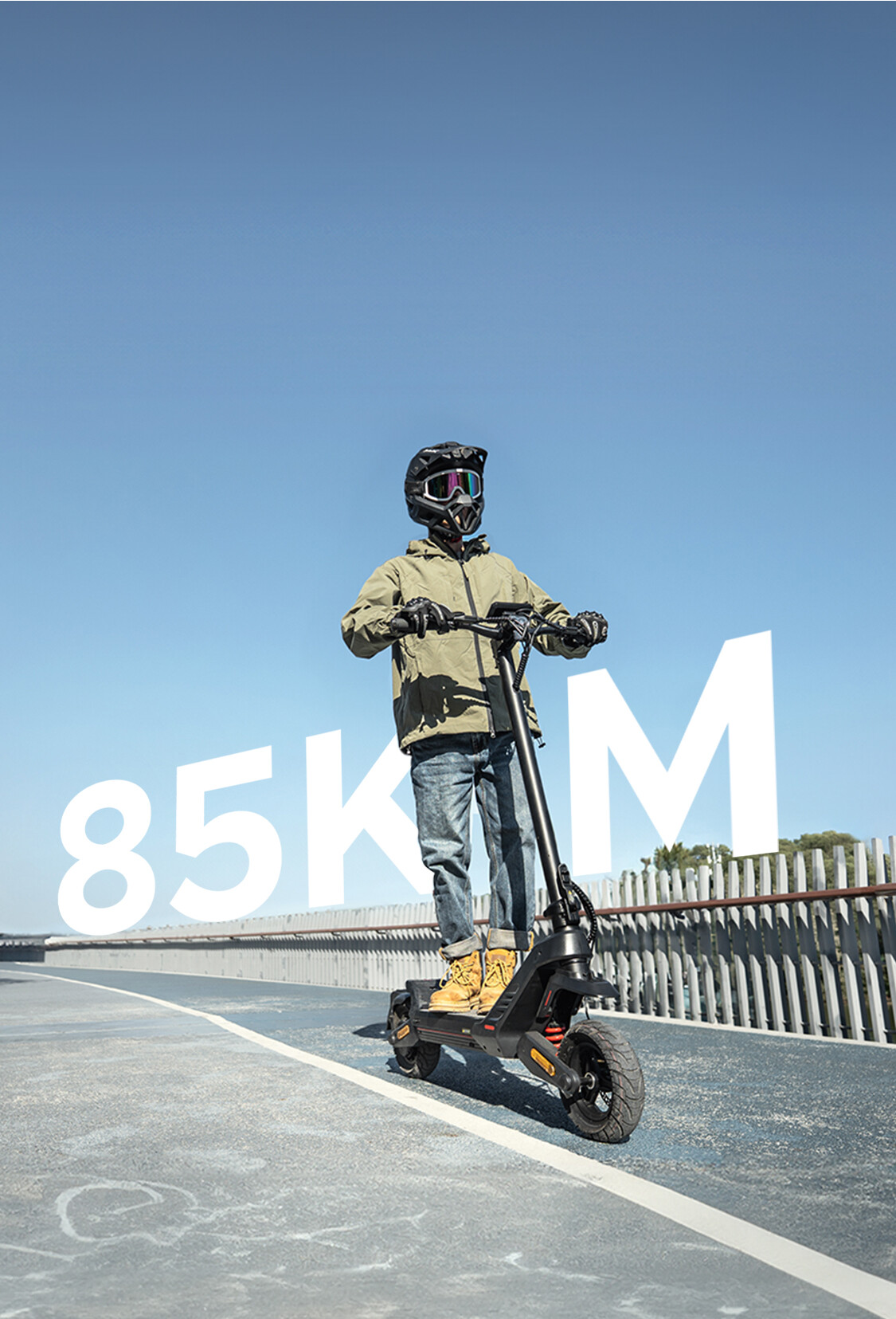 Ein Fahrer mit Helm auf einem E-Roller auf einem blauen Weg unter klarem Himmel mit dem Text '85KM' im Hintergrund.