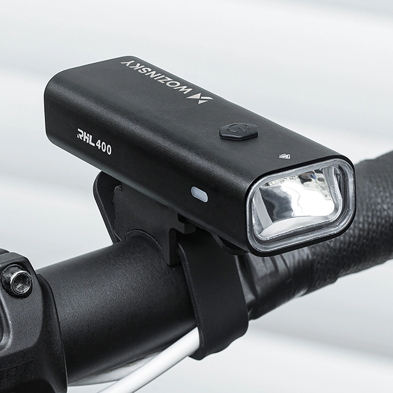 Eine schwarze Wozinsky RHL400 Fahrradlampe ist sicher am Lenker eines Fahrrads montiert.