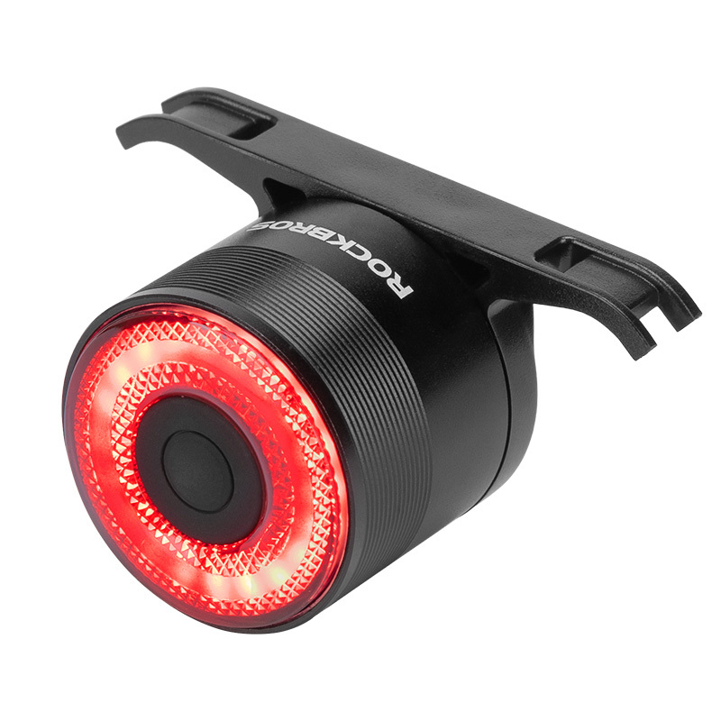 Un feu arrière de vélo RockBros noir avec un cercle LED rouge lumineux et un support de fixation, isolé sur fond blanc.
