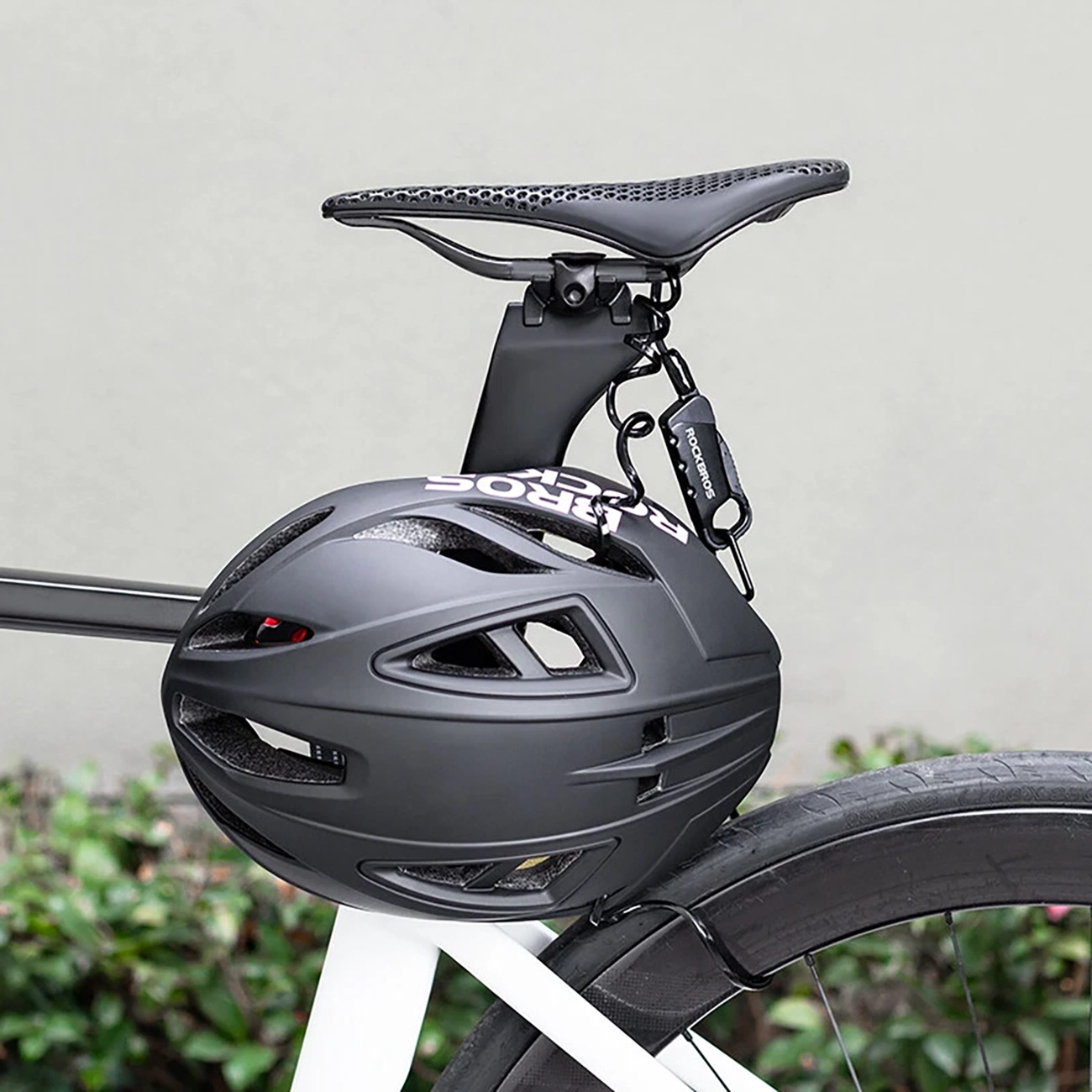 Ein schwarzer Fahrradhelm hängt sicher befestigt am Sattel eines weißen Fahrrads.