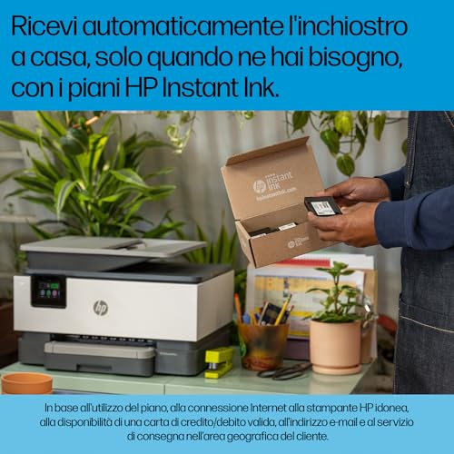 Una persona tiene in mano una scatola HP Instant Ink davanti a una stampante e piante.
