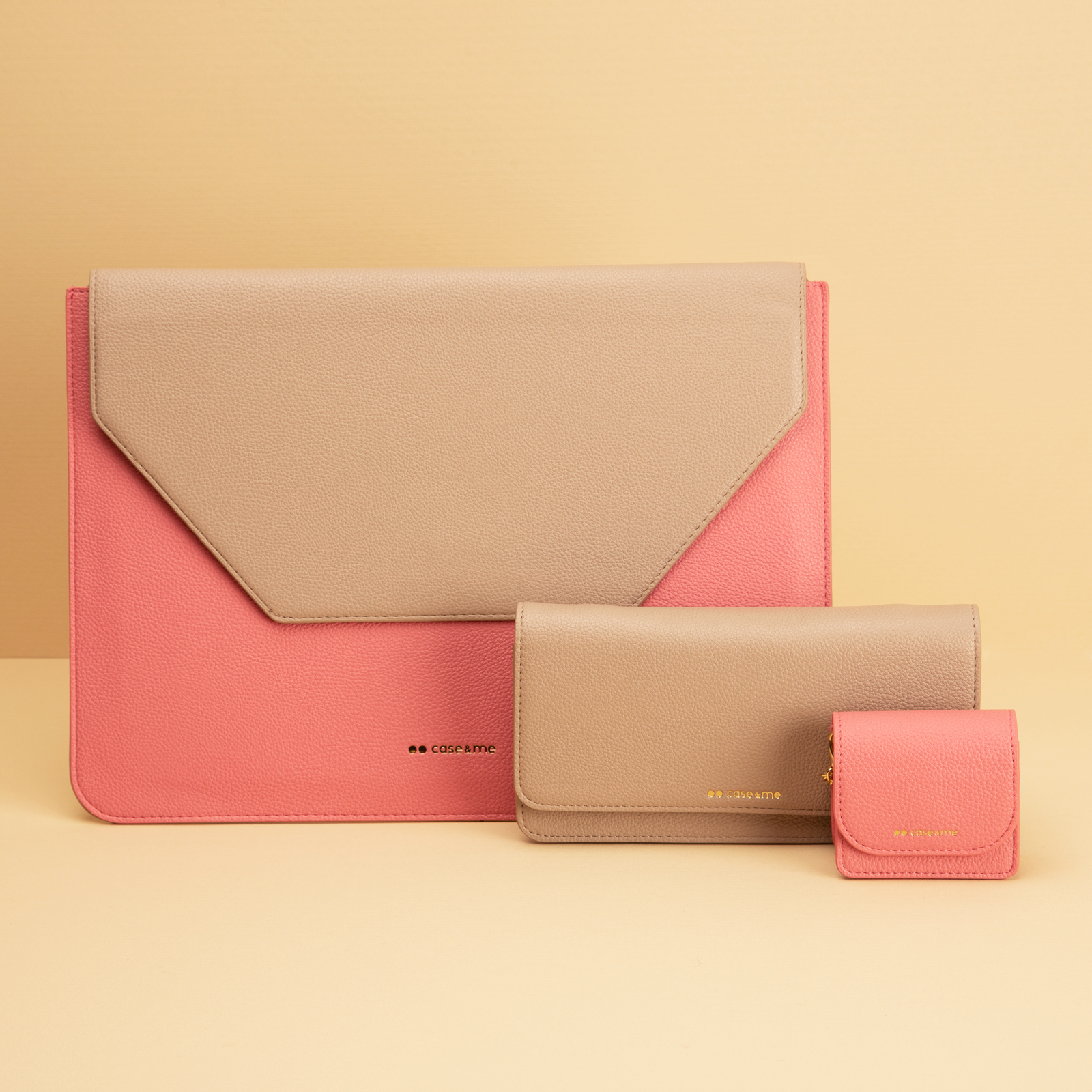Tres fundas de cuero rosa y beige con logotipos dorados sobre fondo beige.