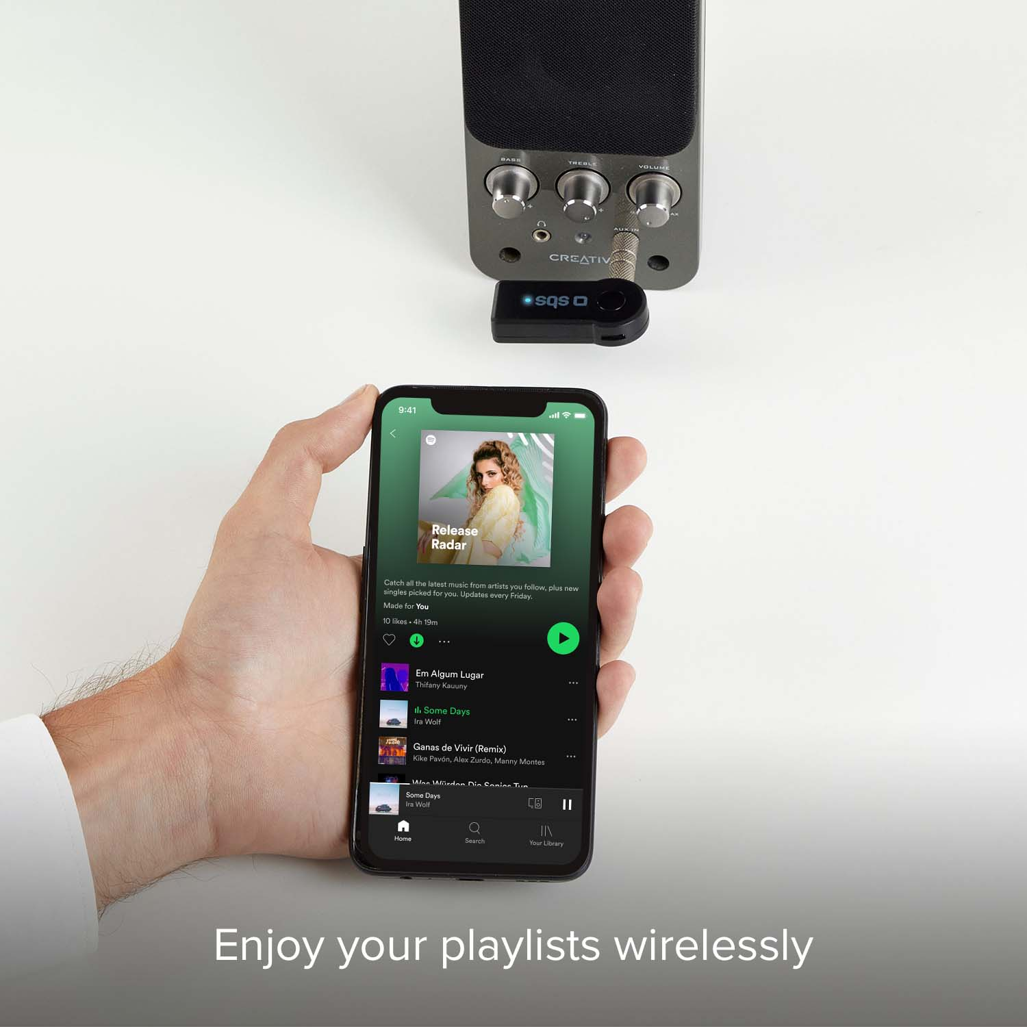 Mano regge uno smartphone con app musicale collegato a un altoparlante.